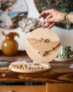 Drewniana dekoracja ścienna w kształcie koła z nałożoną sylwetką ćmy 3D. Rękodzieło wykonane z jasnej sklejki o unikalnym usłojeniu. Produkt zawieszony na naturalnym sznurku. Niepowtarzalny wzór.