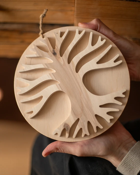 Drewniana dekoracja ścienna w dłoniach przedstawiająca rozłożyste Drzewo Życia 3D. Rękodzieło z jasnej sklejki liściastej o unikalnym usłojeniu, zawieszone na sznurku jutowym. Niepowtarzalny wzór na bazie koła.