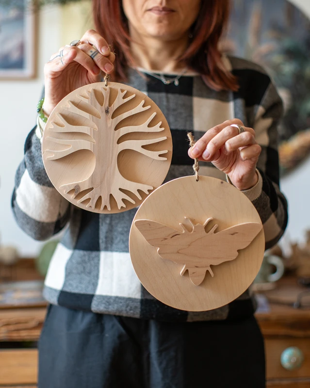 Drewniana dekoracja ścienna w dłoniach przedstawiająca rozłożyste Drzewo Życia 3D. Rękodzieło z jasnej sklejki liściastej o unikalnym usłojeniu, zawieszone na sznurku jutowym. Niepowtarzalny wzór na bazie koła.